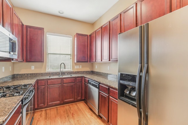 kitchen featuring dark brown cabinets, stainless steel appliances, light wood-style flooring, and a sink