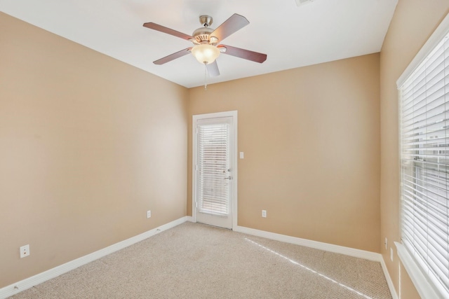 spare room featuring light colored carpet, baseboards, and ceiling fan