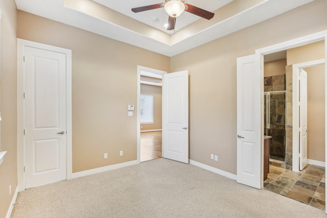 unfurnished bedroom featuring baseboards, a raised ceiling, and carpet