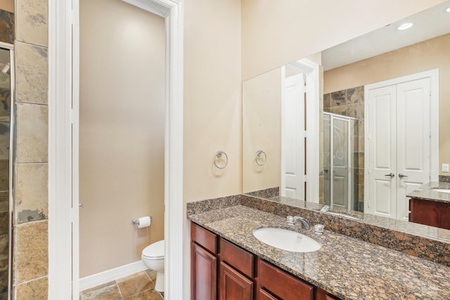 full bath featuring a stall shower, toilet, vanity, and baseboards