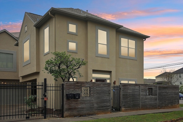 exterior space featuring stucco siding, fence, and a gate