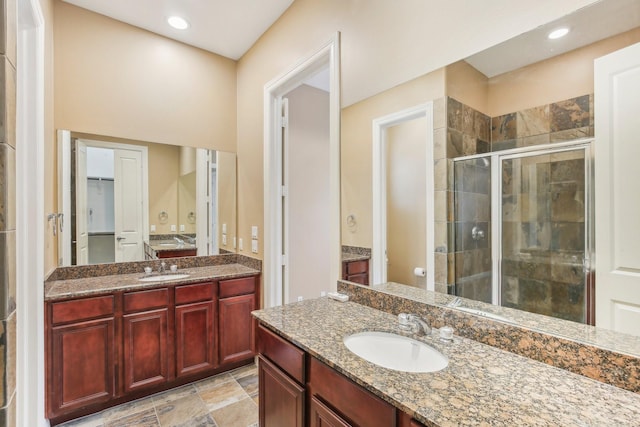 full bath with two vanities, recessed lighting, a stall shower, and a sink