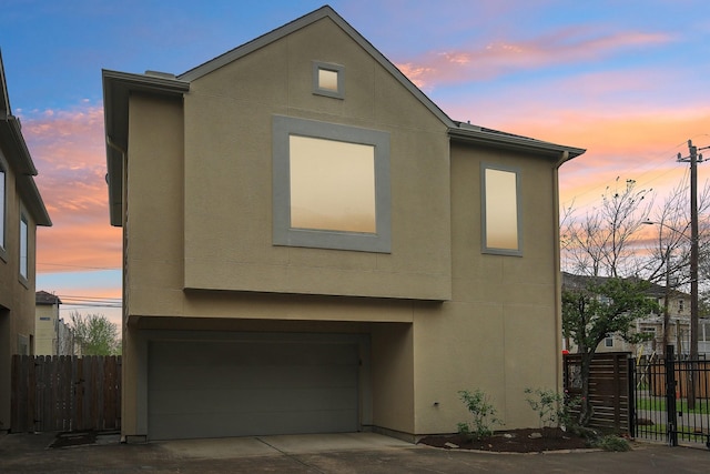 view of front of property with stucco siding, an attached garage, and fence