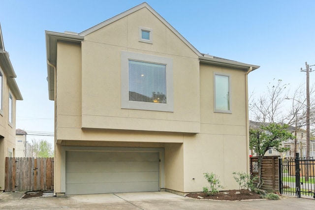 view of front of home with concrete driveway, an attached garage, fence, and stucco siding