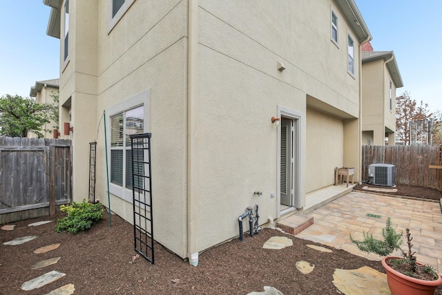 back of property with a patio, central air condition unit, fence, and stucco siding