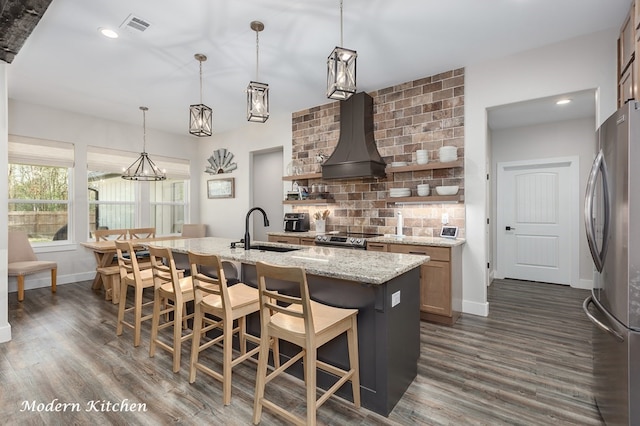 kitchen featuring visible vents, a sink, custom range hood, appliances with stainless steel finishes, and tasteful backsplash