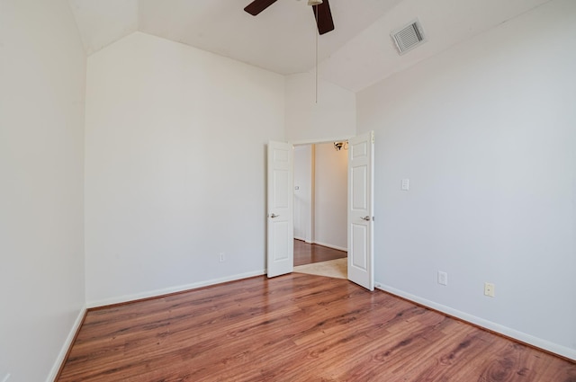 spare room featuring visible vents, ceiling fan, baseboards, lofted ceiling, and wood finished floors