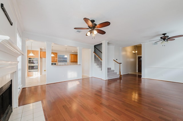 unfurnished living room with light wood-style floors, ceiling fan, and a tile fireplace