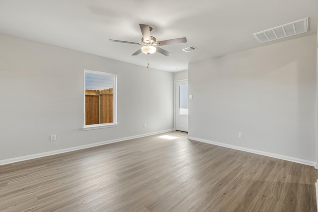 empty room with visible vents, ceiling fan, baseboards, and wood finished floors