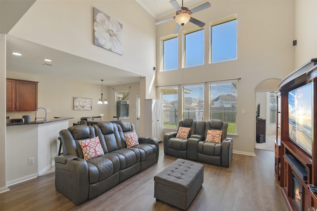 living room featuring recessed lighting, crown molding, baseboards, ceiling fan, and dark wood-style flooring