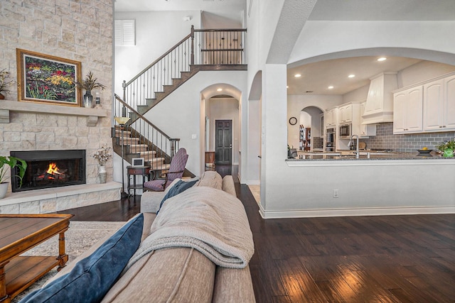 living room with stairway, wood-type flooring, a high ceiling, a fireplace, and baseboards