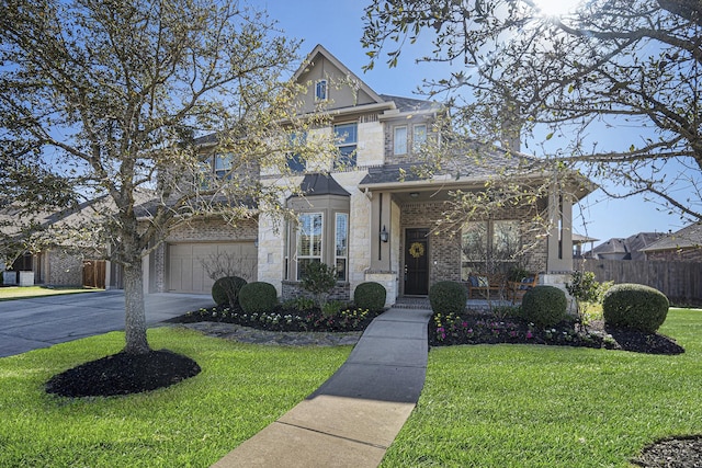 view of front facade featuring stone siding, concrete driveway, a front yard, and fence