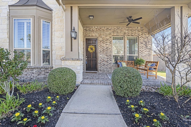 entrance to property with brick siding, stone siding, and a ceiling fan