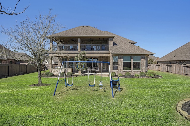 rear view of house featuring a fenced backyard, ceiling fan, a playground, and a balcony