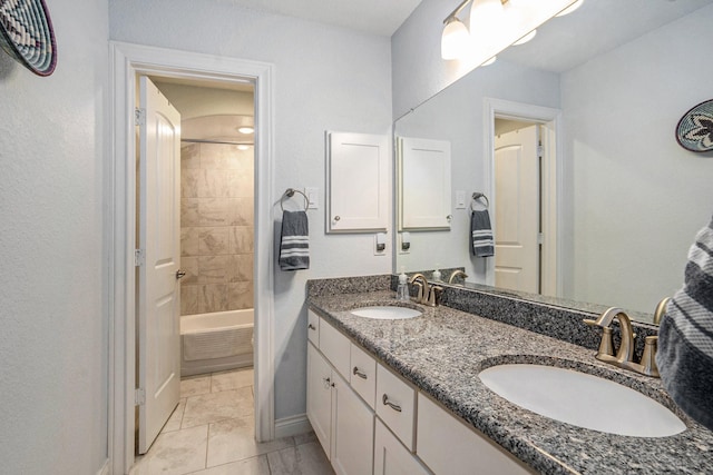 bathroom with double vanity, shower / bathing tub combination, baseboards, and a sink