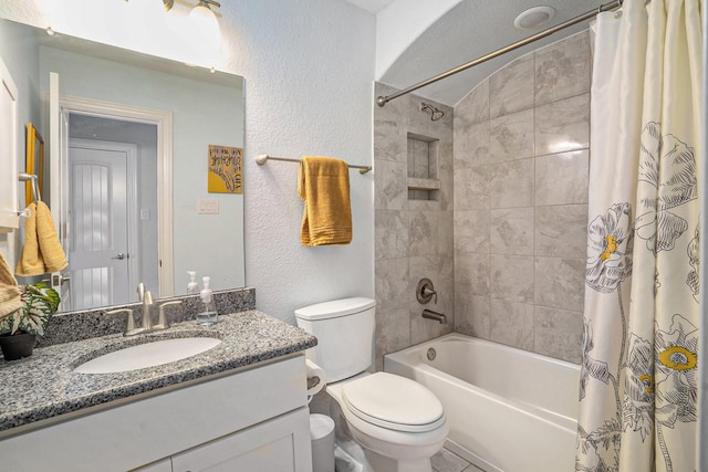 bathroom featuring toilet, vanity, shower / tub combo, and a textured wall