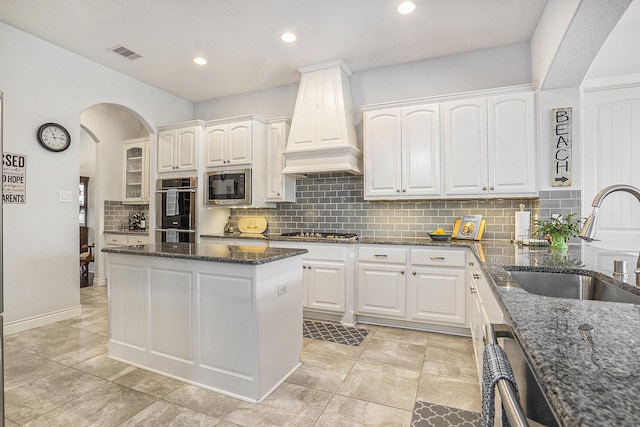 kitchen with visible vents, premium range hood, appliances with stainless steel finishes, white cabinets, and a sink