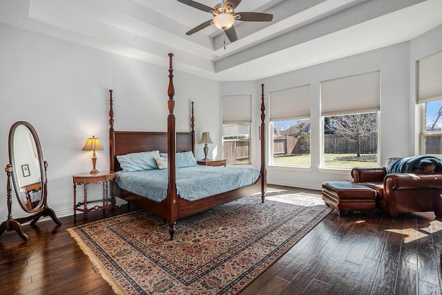 bedroom featuring a tray ceiling, baseboards, ceiling fan, and hardwood / wood-style flooring