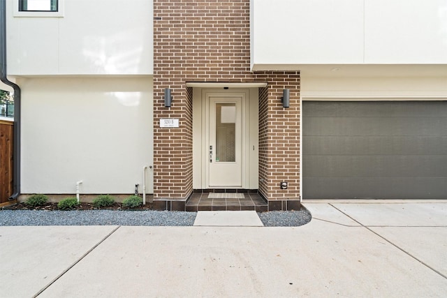 entrance to property featuring brick siding and a garage