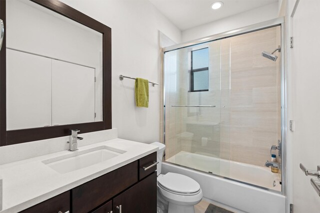 bathroom with toilet, vanity, and shower / bath combination with glass door