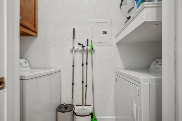 clothes washing area featuring electric panel, cabinet space, washer and clothes dryer, and a textured wall