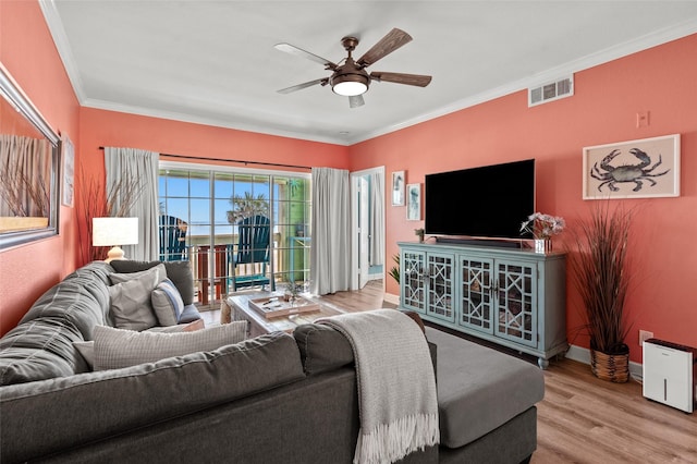 living room with wood finished floors, baseboards, visible vents, ceiling fan, and crown molding