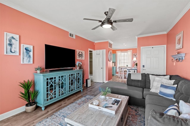 living area with ceiling fan, visible vents, wood finished floors, and crown molding