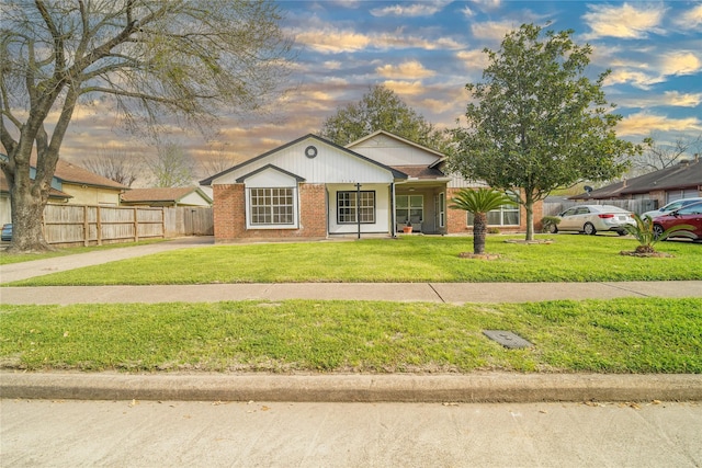 view of front facade featuring brick siding, a front lawn, and fence