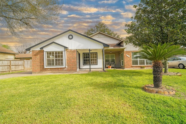 view of front of house featuring a yard, fence, and brick siding