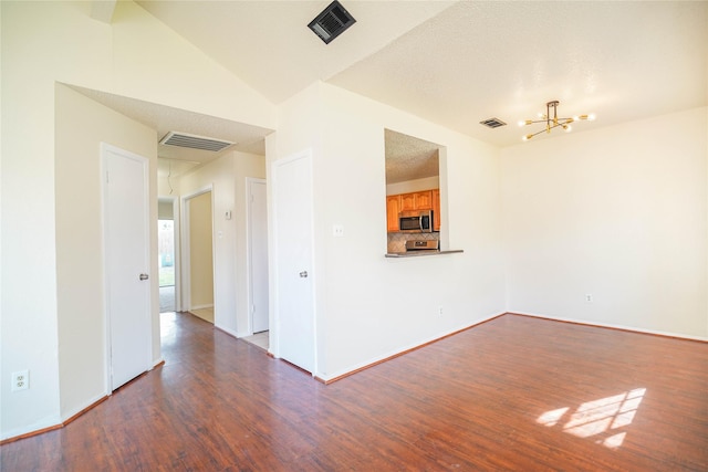 empty room featuring a notable chandelier, visible vents, and wood finished floors