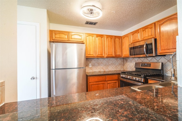 kitchen featuring visible vents, decorative backsplash, appliances with stainless steel finishes, a textured ceiling, and a sink