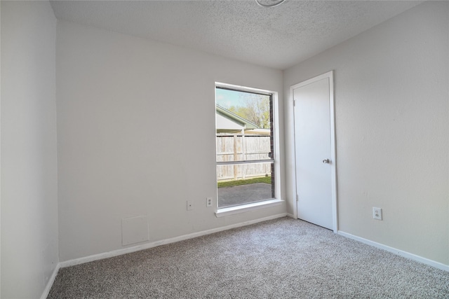 carpeted spare room with a textured ceiling and baseboards