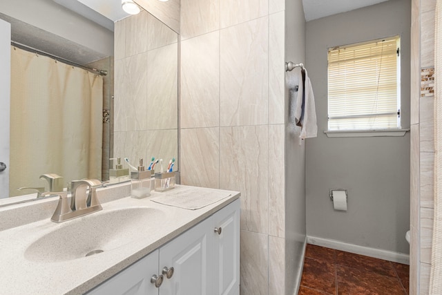 full bath with vanity, tile walls, and baseboards