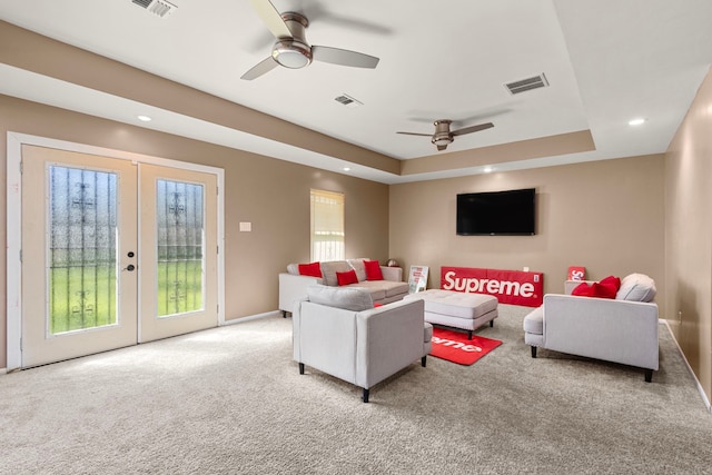 carpeted living room with a raised ceiling, french doors, visible vents, and ceiling fan