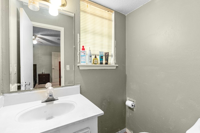 bathroom with a textured ceiling, vanity, a ceiling fan, and a textured wall