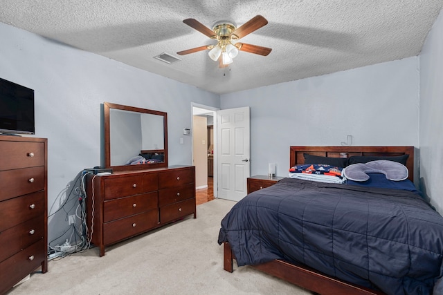 bedroom with a ceiling fan, carpet, visible vents, and a textured ceiling