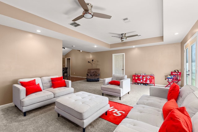 living area with a tray ceiling, visible vents, baseboards, and a ceiling fan