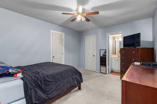 bedroom featuring a textured ceiling, ceiling fan, ensuite bathroom, and light carpet