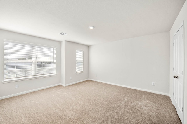 unfurnished room with light colored carpet, visible vents, and baseboards