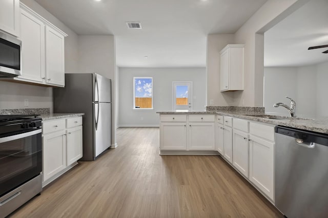 kitchen featuring visible vents, a peninsula, a sink, appliances with stainless steel finishes, and light wood-type flooring