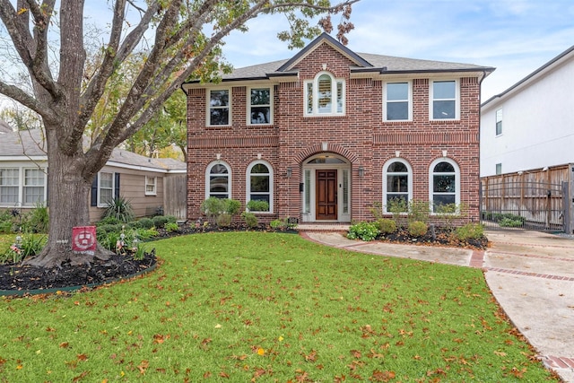 view of front of home featuring brick siding, a front yard, and fence