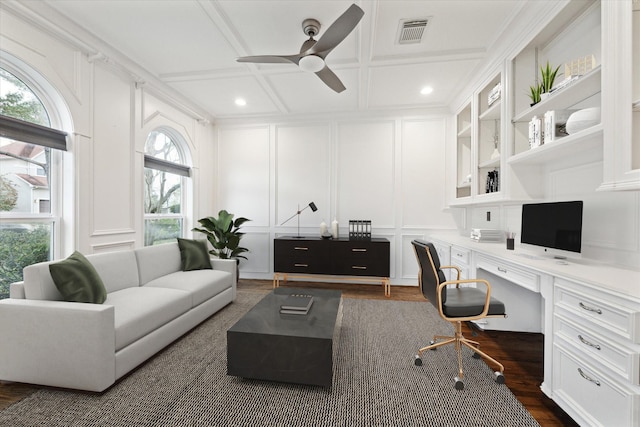 office space with visible vents, coffered ceiling, built in desk, a decorative wall, and ceiling fan