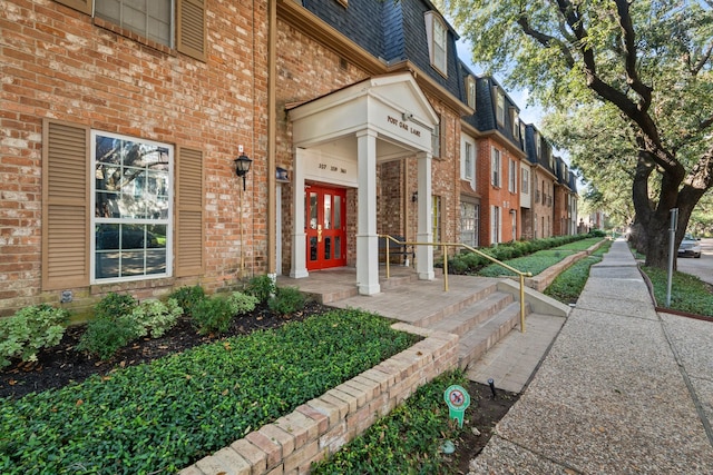 doorway to property with mansard roof, french doors, brick siding, and a residential view