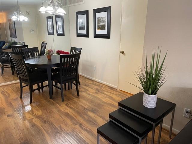 dining space with baseboards, an inviting chandelier, and wood finished floors