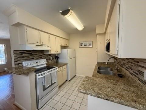 kitchen featuring white appliances, a sink, decorative backsplash, under cabinet range hood, and white cabinetry