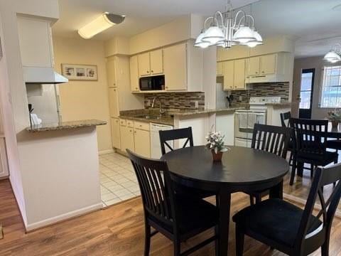 dining space with light wood-type flooring, baseboards, and an inviting chandelier