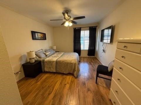 bedroom with crown molding, ceiling fan, and wood finished floors