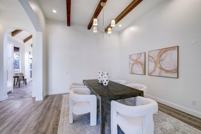 dining room featuring arched walkways, beamed ceiling, light wood-type flooring, and a notable chandelier