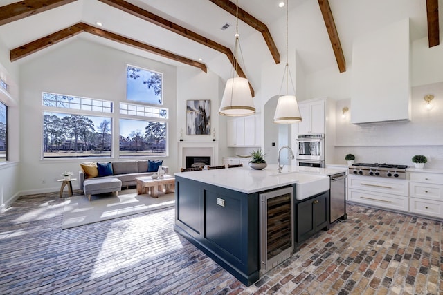 kitchen featuring high vaulted ceiling, stainless steel appliances, light countertops, wine cooler, and white cabinets