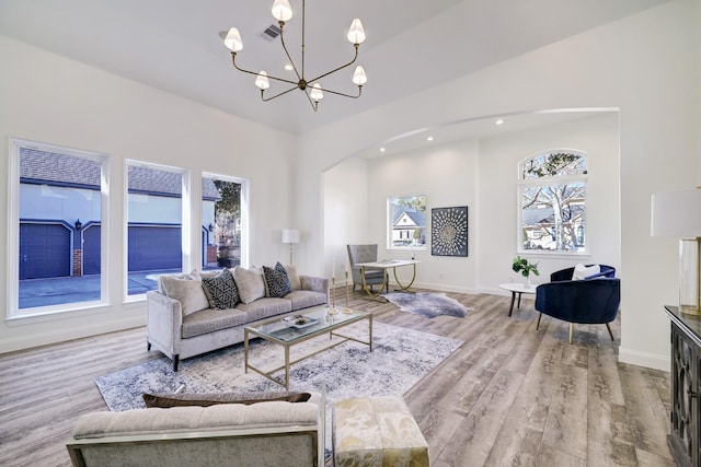living area featuring visible vents, wood finished floors, arched walkways, baseboards, and a chandelier